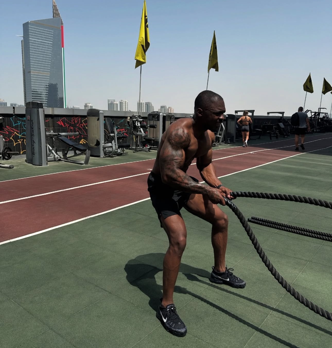 Athlete training with battle ropes on a rooftop performance track